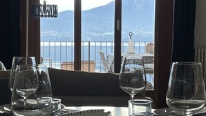 Une table à manger dressée avec des verres à vin, des assiettes et des couverts, donnant sur un paysage montagneux à travers une grande fenêtre.