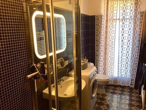 Bathroom features a glass-enclosed shower, sink, toilet, and washing machine.