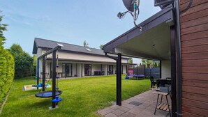 Ein überdachter Patio-Bereich mit Schaukeln, einem Grill und einem Haus im Hintergrund.