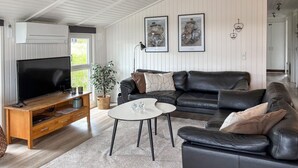 A living room with a TV, leather sofa, coffee table, and a potted plant. - Awesome home in Ringkøbing with sauna (Ringkøbing)