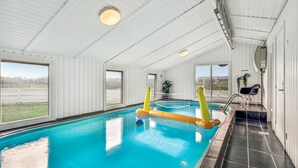 An indoor swimming pool with clear blue water, surrounded by white walls and large windows. - Awesome home in Ringkøbing with sauna (Ringkøbing)