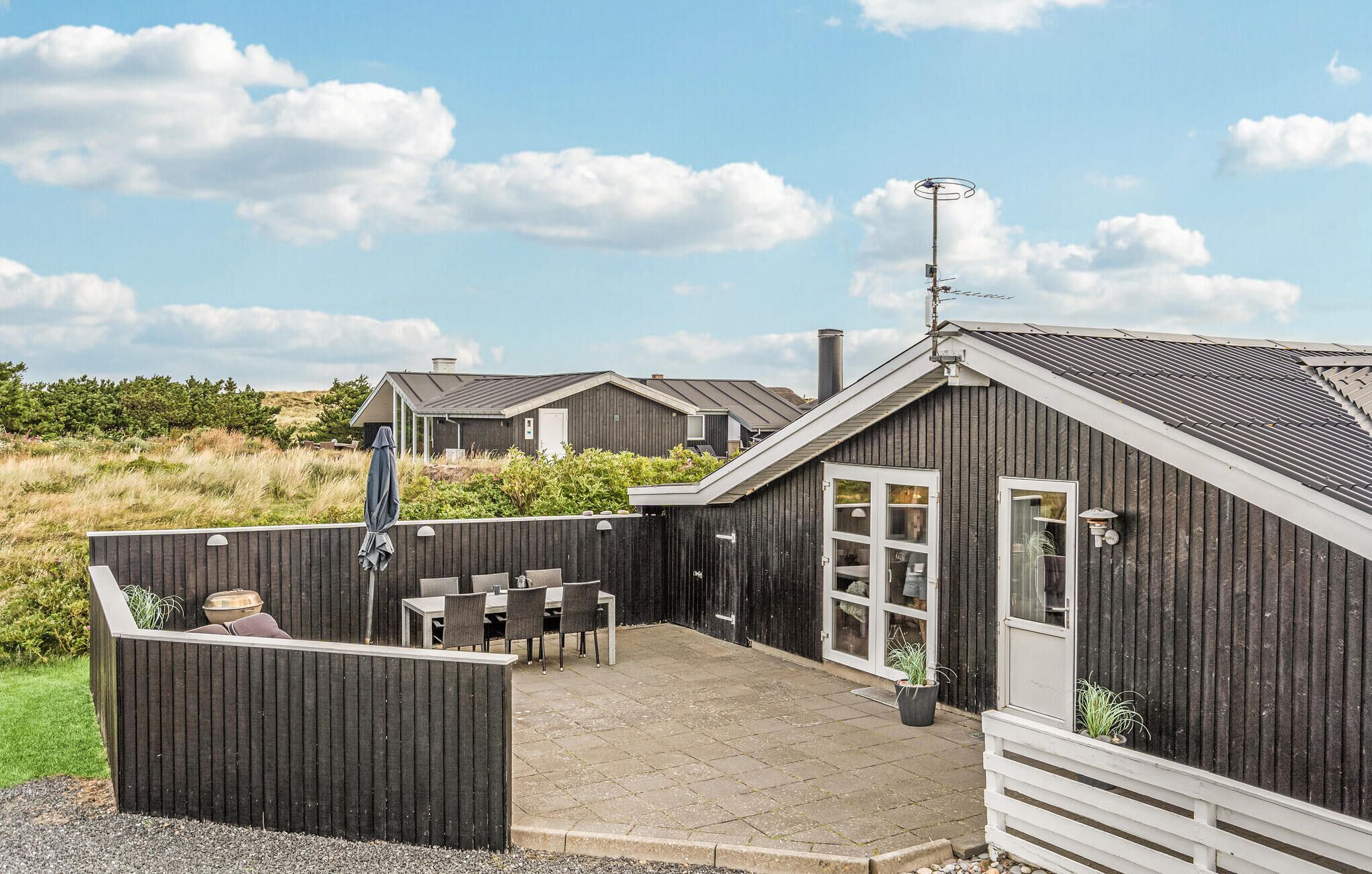 A wooden building with a patio area, outdoor seating, and a small garden.