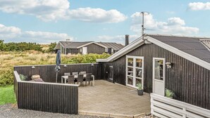 A wooden building with a patio area, outdoor seating, and a small garden. - Awesome home in Ringkøbing with sauna (Ringkøbing)