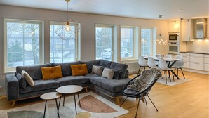 En moderne stue med en hjørnesofa, et spiseområde og et køkken.