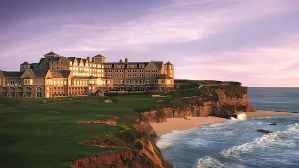 A large, multi-story hotel with a grand entrance, situated on a cliff overlooking the ocean. - Coastal Retreat - 3,000 sqft, Pets Ok, Walk 2 Beach & Tidepools, Surf, see Seals (Moss Beach)