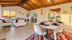 A spacious living area with a dining table set for four, a sofa, and a television. - Coastal Retreat - 3,000 sqft, Pets Ok, Walk 2 Beach & Tidepools, Surf, see Seals (Moss Beach)