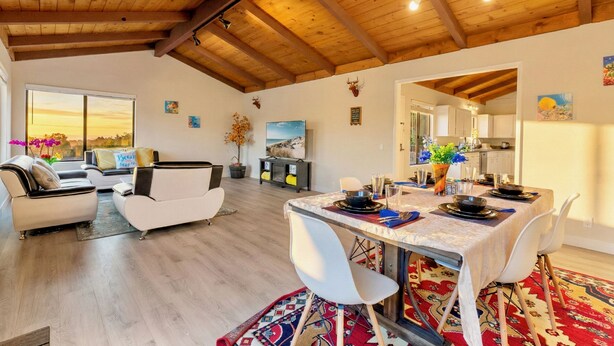 Un vaste espace de vie comprenant une table à manger pour quatre personnes, un canapé et un téléviseur.
