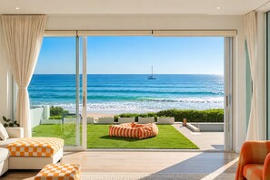 A modern living room with a large glass door leading to a balcony overlooking a beach and ocean. - Henley Beachfront Luxury Home With Private Pool, Spa And Sauna! (Henley Beach South)
