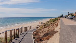 Ein Küstenweg mit Holzwand, befestigter Wege und einem Strand im Hintergrund.