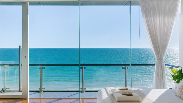 Ein Balkon mit Glastür und Blick auf das Meer.