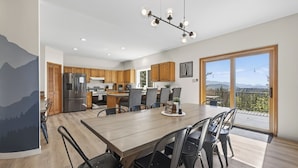 A modern kitchen with wooden cabinets, a stainless steel refrigerator, and a dining area with a wooden table and chairs.