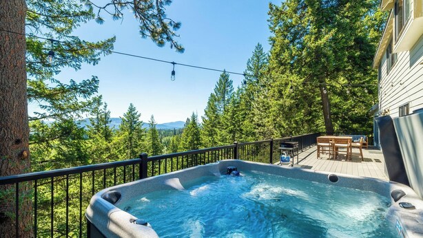A hot tub on a deck with a view of a forest and mountains.