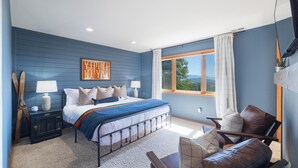 A bedroom with a bed, bedside tables, a chair, and a window with curtains.