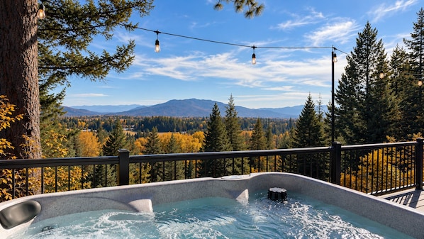 A hot tub with a view of a forest and mountains.