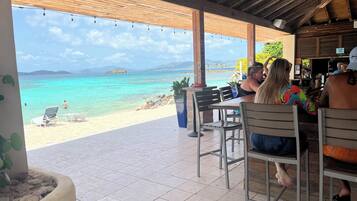 Un restaurant situé en bord de mer, avec une terrasse offrant une vue sur les eaux turquoise et les îles lointaines.