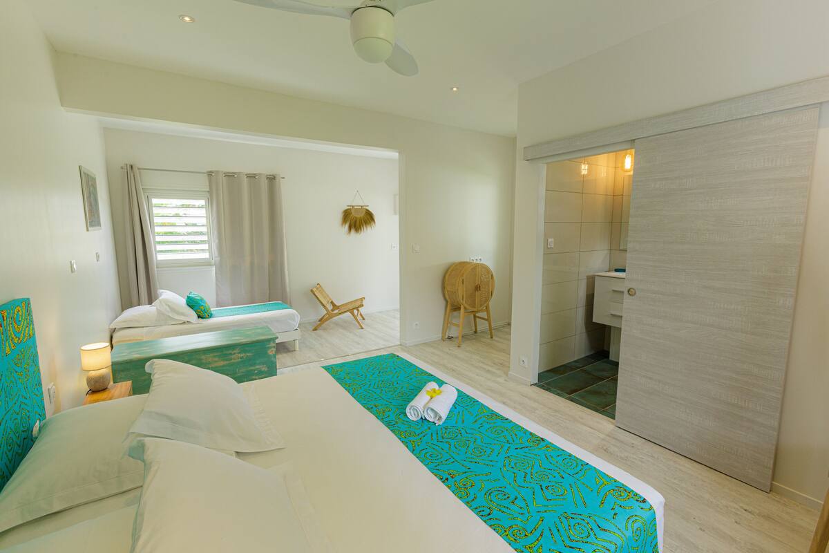 A hotel room with two beds, a bathroom, and a sitting area.