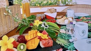 A tropical-themed buffet with a variety of fruits, flowers, and a woven basket. - FARE VAVAE (Raiatea)