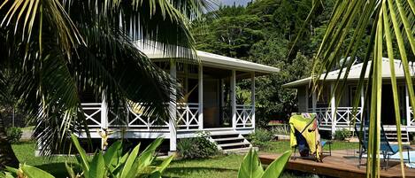 A tropical resort with a white building featuring a covered porch and a pool area.