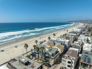 Una zona residenziale sul lungomare con proprietà direttamente sulla spiaggia, una spiaggia sabbiosa e onde oceaniche.