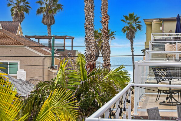 Un balcon aménagé avec du mobilier d’extérieur, des palmiers et une vue sur l’océan.