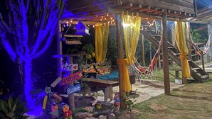 A wooden house with a porch decorated with yellow curtains and string lights.