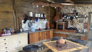 A rustic kitchen with wooden cabinets, a brick oven, and various cooking utensils.