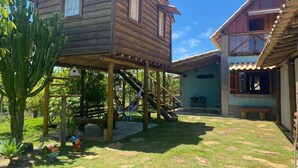 A wooden house with a patio, a small play area with a slide, and a cactus plant.
