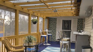 A covered patio with a blue carpet, wooden furniture, and a hanging plant. - Delightful, 4BR 2.5BA ranch style near Parks, trails, shops, malls, Restaurants. (Lithonia)