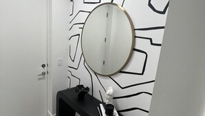 A hallway with a black console table, a round mirror, and a white door. - Apartment in Sarasota (Sarasota)