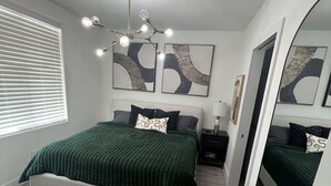 A modern bedroom with a bed, bedside tables, a mirror, and abstract wall art. - Apartment in Sarasota (Sarasota)