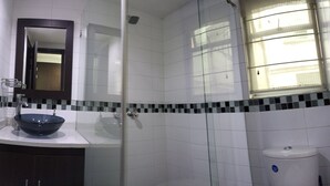 A bathroom with a glass shower enclosure, a sink with a dark basin, and a toilet. - Privated room with bathroom (Bogotá)
