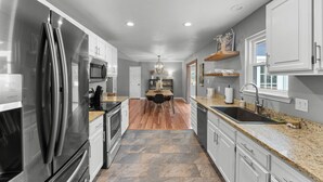 A modern kitchen with stainless steel appliances, granite countertops, and a central island with seating. - Beaver Lake Getaway-15 min from downtown Rogers with HOT TUB! (Rogers)