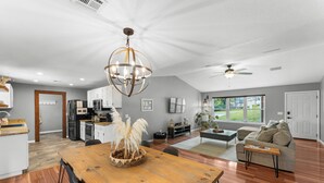 A spacious living area with a dining table, sofa, and a view of the outdoors. - Beaver Lake Getaway-15 min from downtown Rogers with HOT TUB! (Rogers)