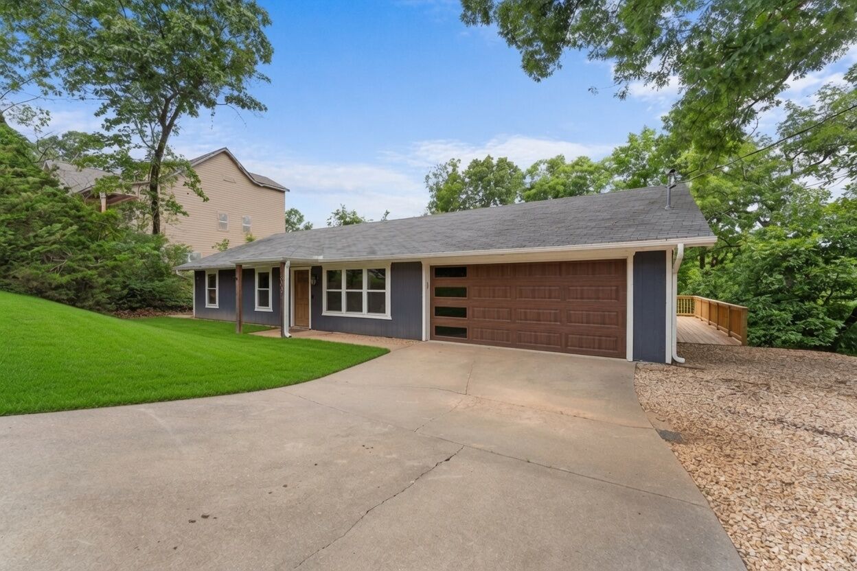 A single-story house with a garage, a driveway, and a well-maintained lawn.