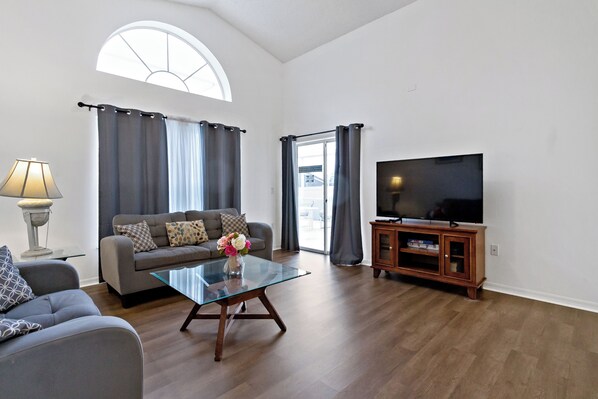 A living room with a sofa, a glass coffee table, a TV, and a wooden cabinet.