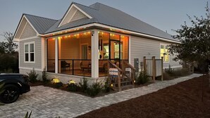 A two-story house with a covered porch, a visible garage, and a driveway. - WATERSHED COTTAGE, MODERN 3BD/2BA HOME W/POOL & FIRE PIT! PET FRIENDLY! (Mexico Beach)