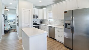 Una cocina moderna con armarios blancos, electrodomésticos de acero inoxidable y una isla central.