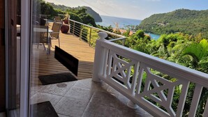 Ein Balkon mit Blick auf das Meer, eine Holzterrasse und ein weißes Geländer.