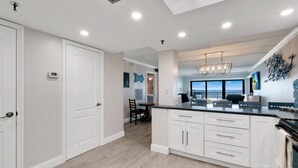 A modern kitchen with white cabinetry, a large island, and a view of the ocean.