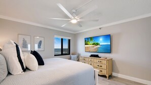 A bedroom with a bed, a ceiling fan, a TV, and a dresser.