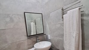A modern bathroom with a white sink, dark vanity, a mirror, and a towel rack. - Yamabeach Stays 3 (Nassau)