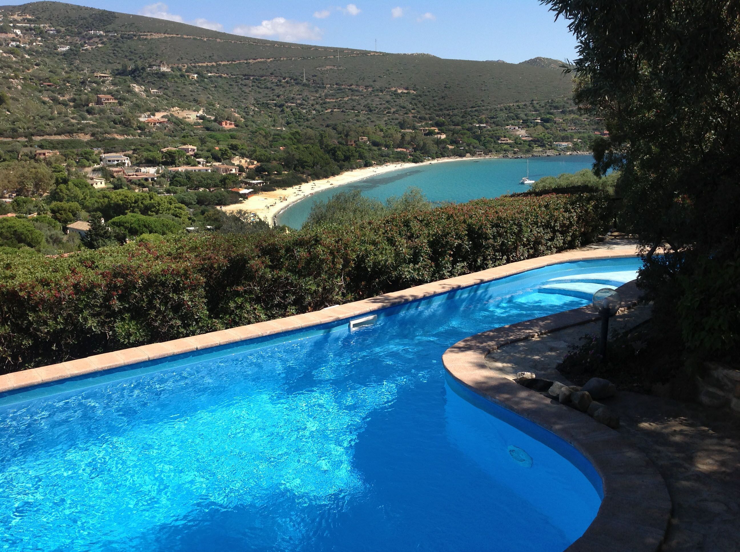 A swimming pool with a view of a beach and a mountainous landscape.