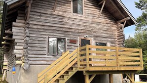 Une cabane en rondins avec un escalier en bois menant à une terrasse.