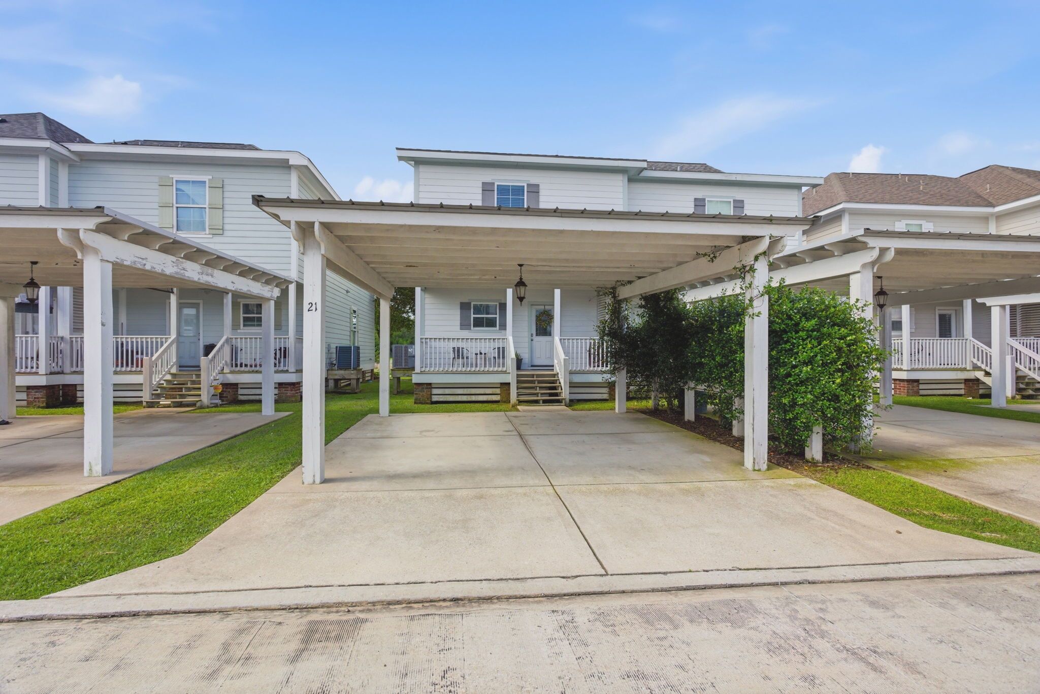 A row of townhouses with covered porches, a central walkway, and a well-maintained lawn.
