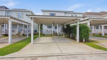 A row of townhouses with covered porches, a central walkway, and a well-maintained lawn.