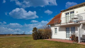 Ein zweistöckiges Haus mit Balkon, befestigter Auffahrt und Rasenfläche.
