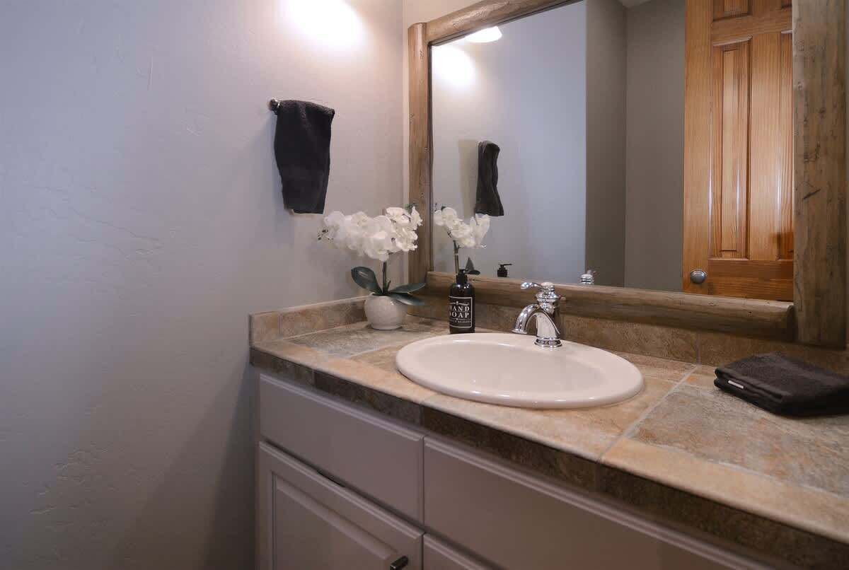 A bathroom with a sink, mirror, and a towel rack.