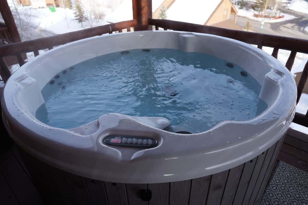 A hot tub on a wooden deck with a digital control panel.