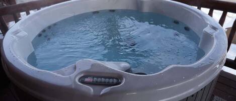 A hot tub on a wooden deck with a digital control panel.