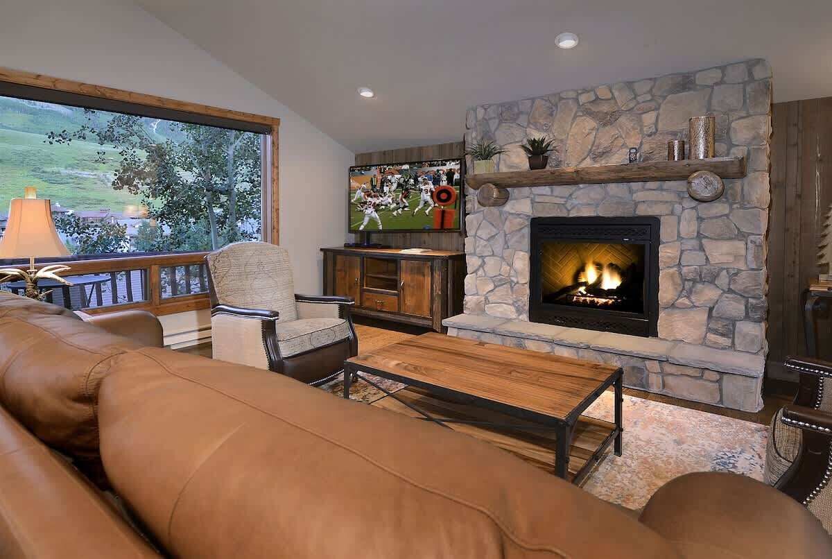 A living room with a stone fireplace, leather sofa, and a television.